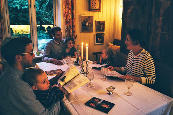 Familie rundt et bord med lysestake og åpen bok