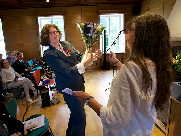 Guri Hjeltnes mottar blomster av styreleder Bente Sandvig i HL-senterets styret.