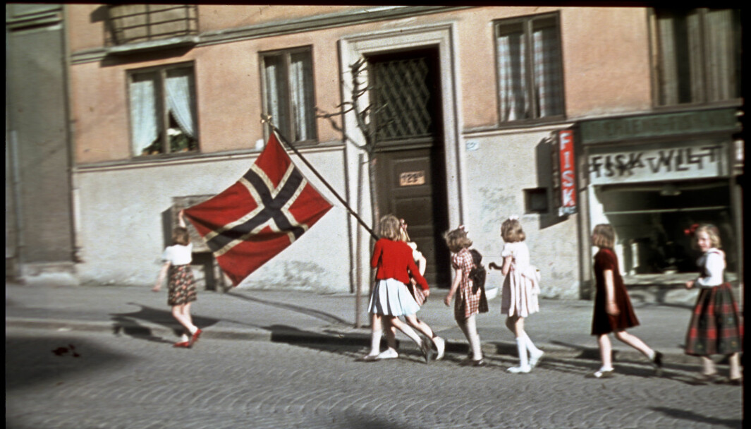 Syv unge jenter går i tog med et norsk flagg