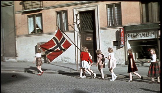 Unge jenter med norsk flagg går i tog