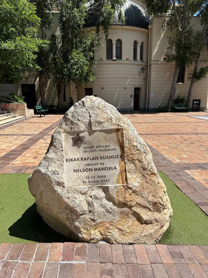 Stone with a sign reading "South African Jewish Museum, Kikar Kaplan Kushlick opened by Nelson Mandela, 13.12.2000, 16 Kisley 5761"