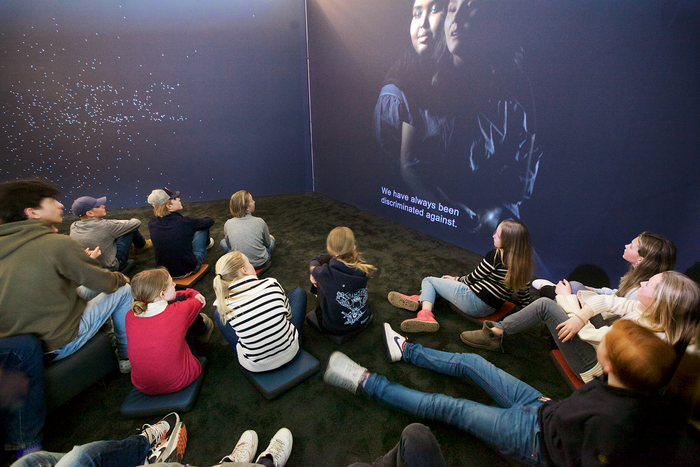 Ungdommer sitter på gulvet i et mørkt rom og ser på en skjerm