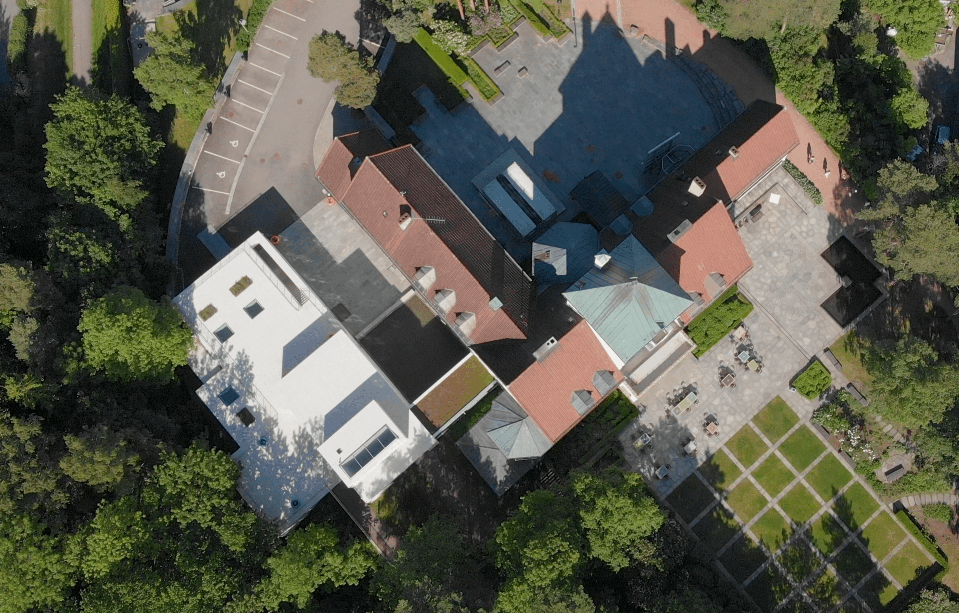 Drone photography of a big white building surrounded by woods.