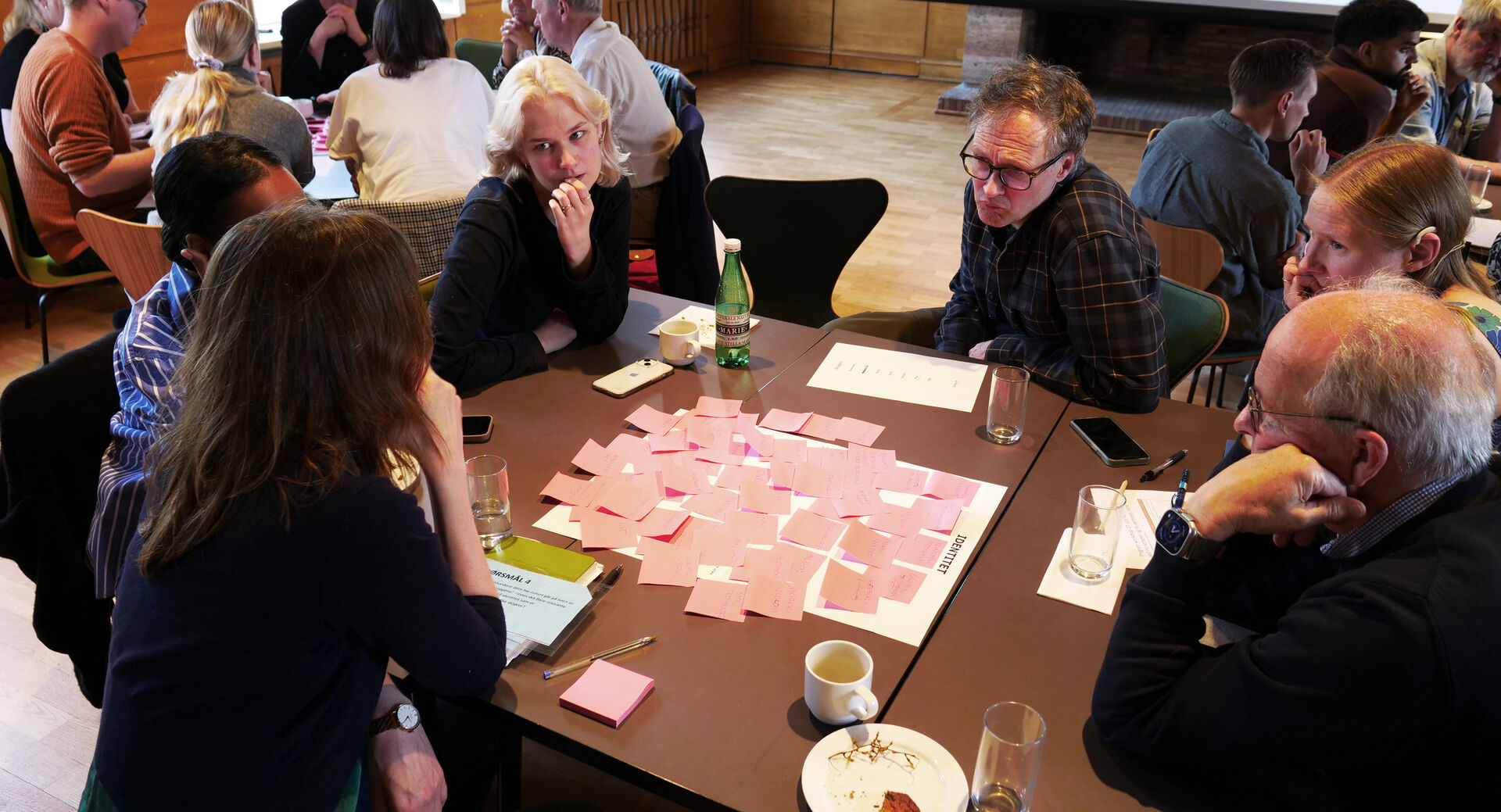 Seks personer i diskusjon rundt et bord med post-it lapper foran seg.